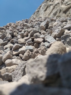 A close-up of rugged construction stones and sand piles under a bright sky.