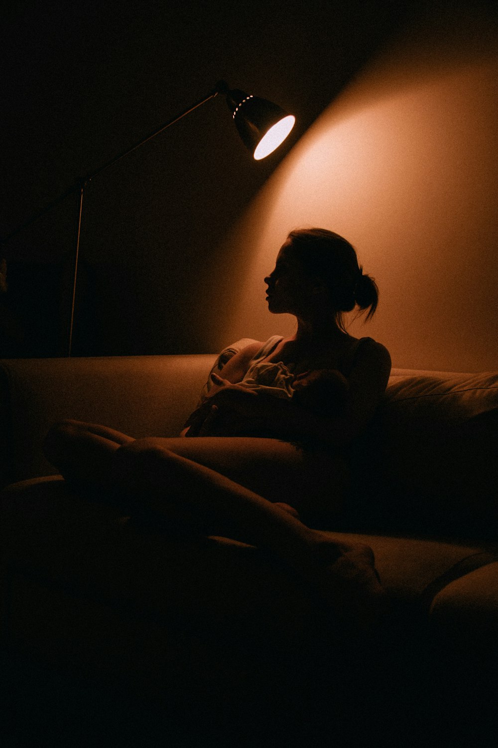 a woman sitting on a couch under a lamp