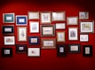 A collection of colorful, framed paintings displayed on a rustic wooden wall.