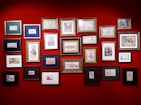 A collection of colorful, framed paintings displayed on a rustic wooden wall.