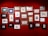 A collection of framed artworks are arranged on a vibrant red wall. The frames vary in size and color, displaying a variety of sketches and paintings, predominantly in black and white with a few color highlights. The artworks seem to include landscapes, portraits, and abstract designs.