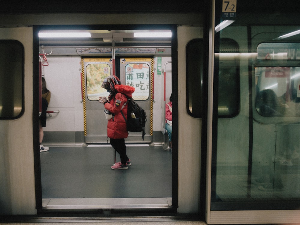 Una donna in un cappotto rosso in piedi su una metropolitana