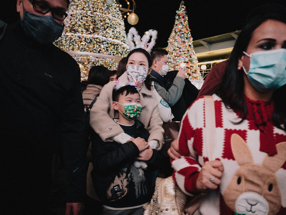 a group of people wearing face masks in front of christmas trees
