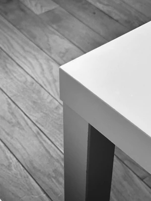 A sleek black and white photo of a modern wooden dining table set in a minimalist room.