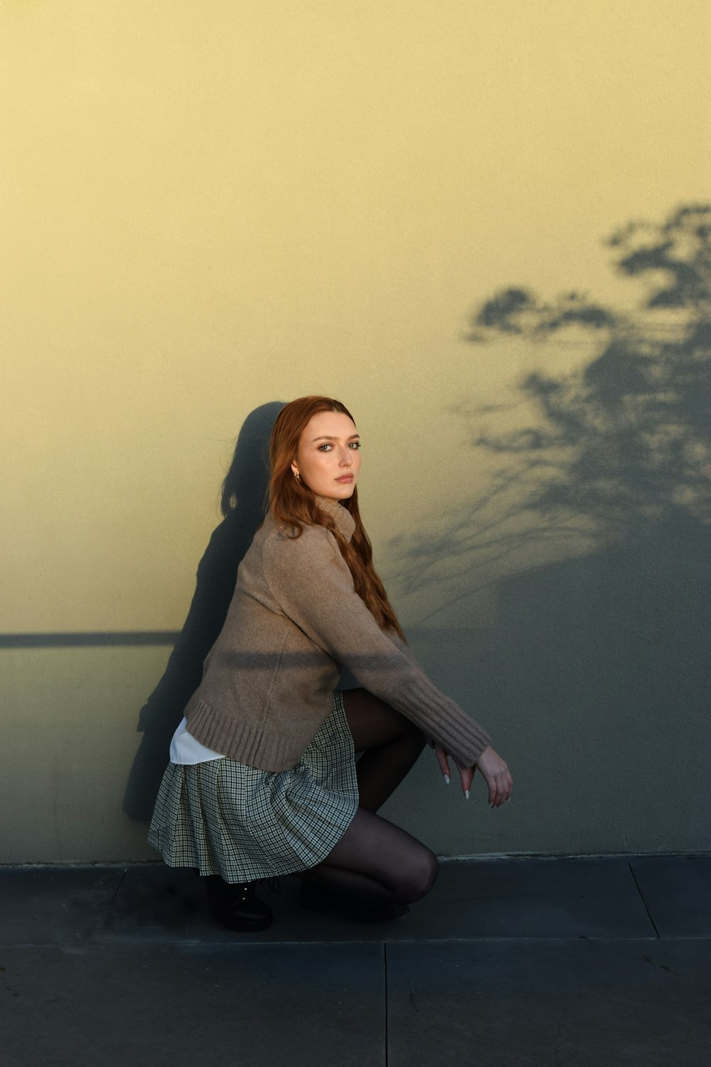 a woman sitting on the ground next to a wall