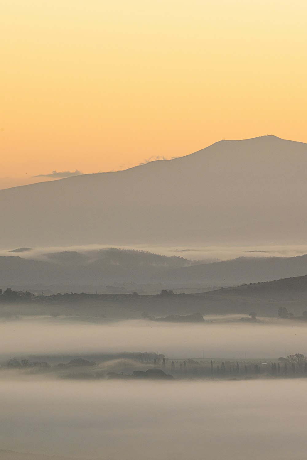 a foggy landscape with mountains in the distance