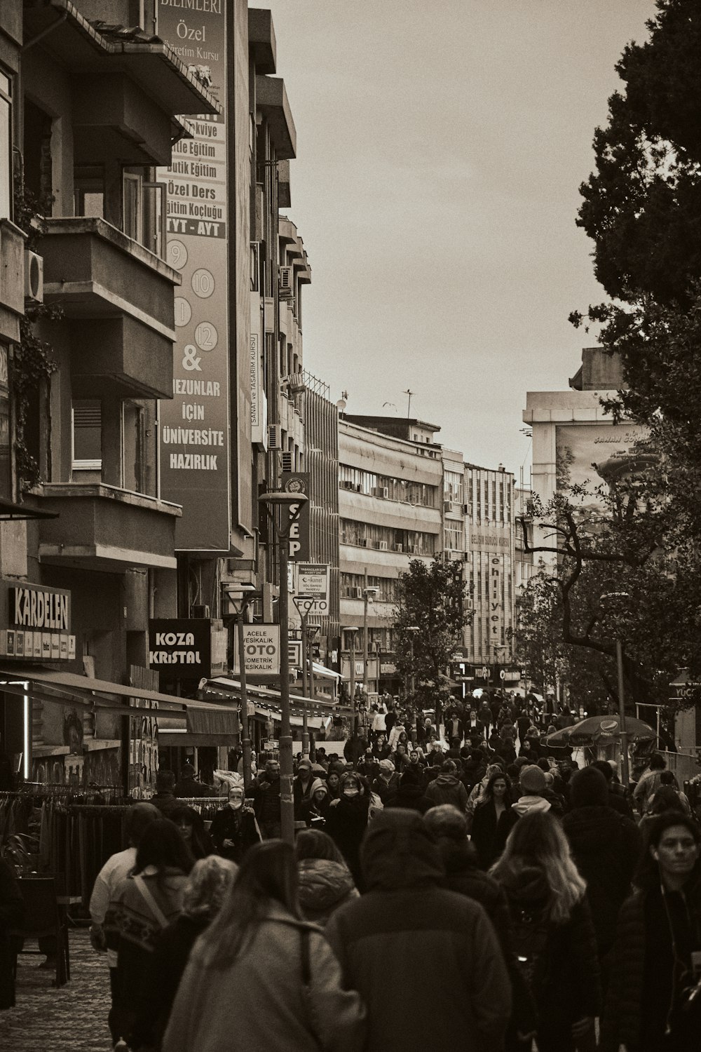 a crowd of people walking down a street next to tall buildings