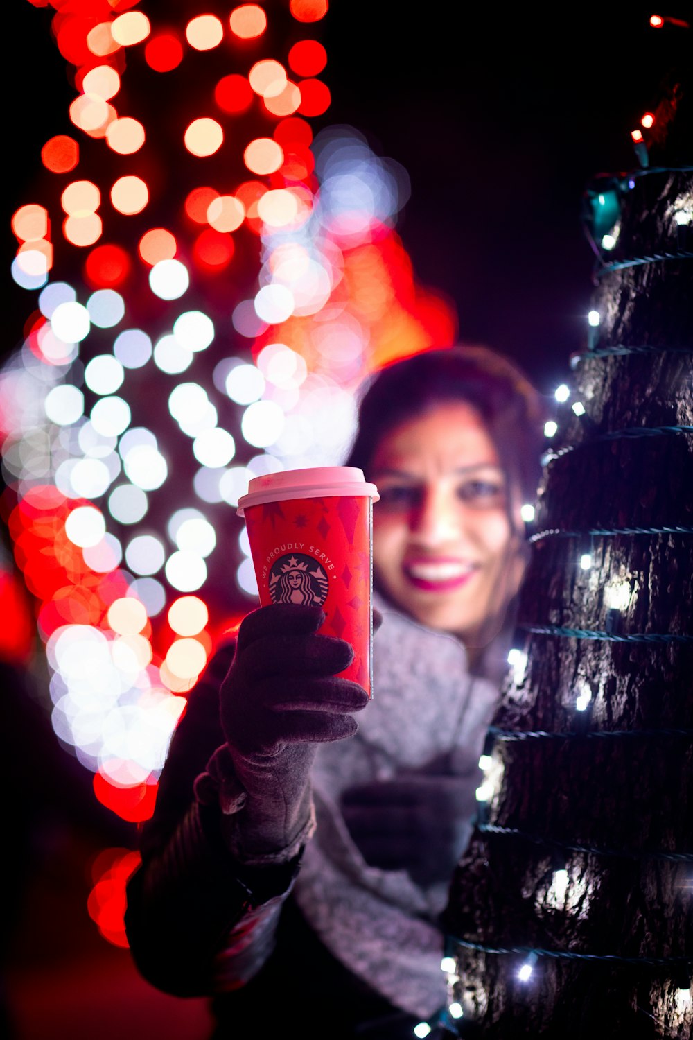 Eine Frau hält eine Tasse Kaffee vor einem Weihnachtsbaum