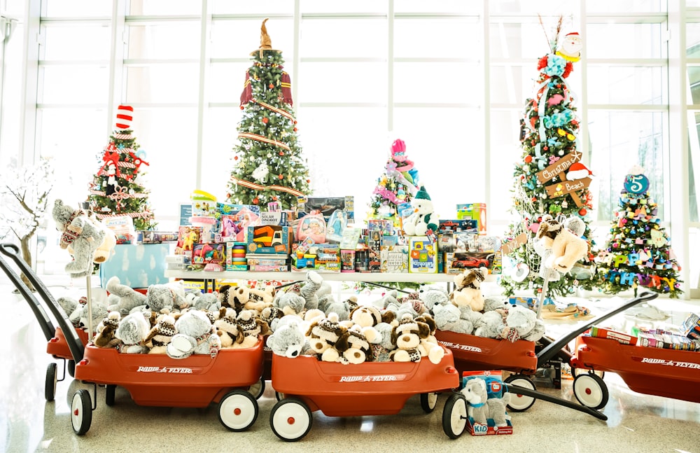 a red wagon filled with stuffed animals next to a christmas tree