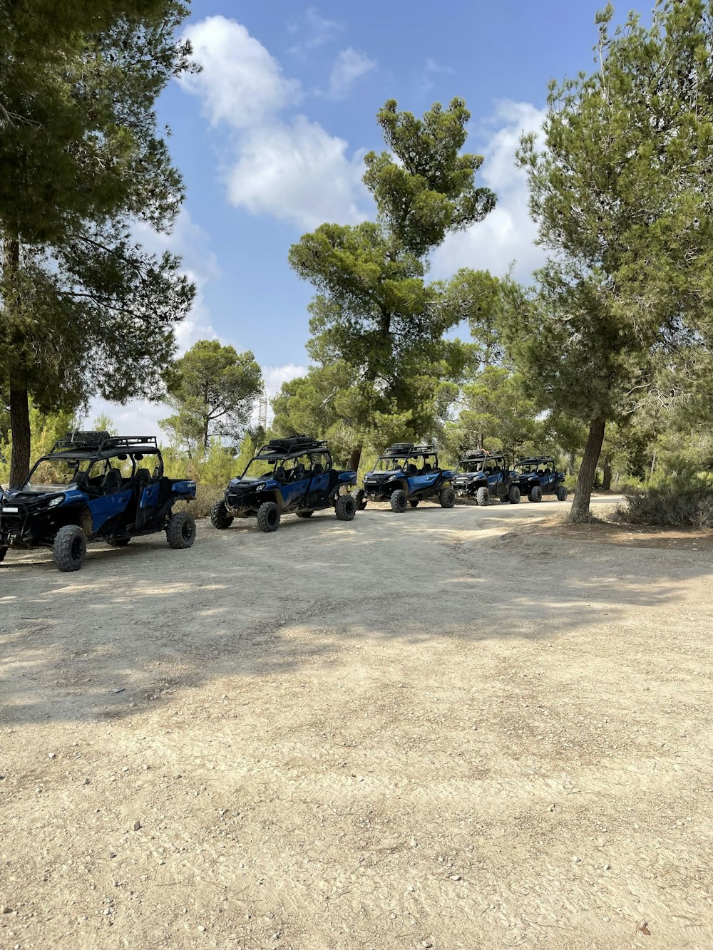 a group of four blue utensils parked on a dirt road