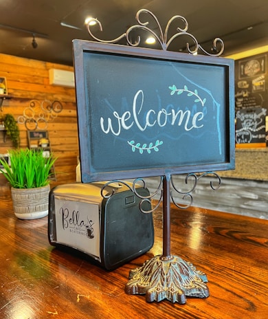A cozy corner with a handwritten 'welcome' sign and a cup of coffee steaming beside it.