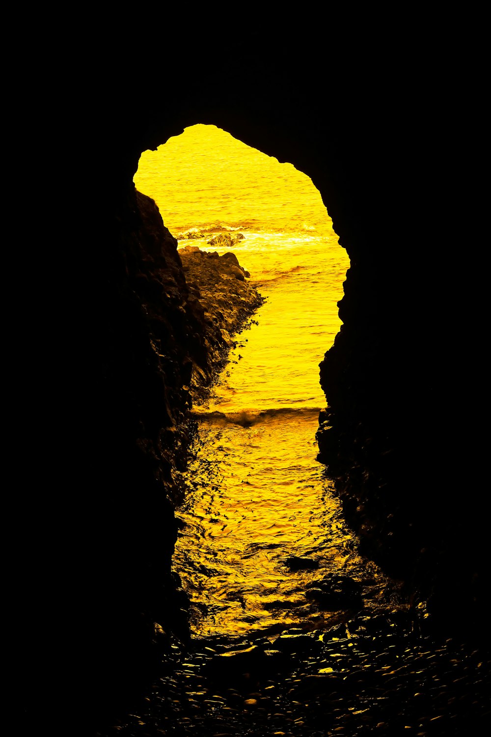 a yellow light shines on the water from a cave
