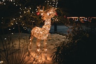 3D reindeer figure with bright LED lights standing on a snowy lawn.