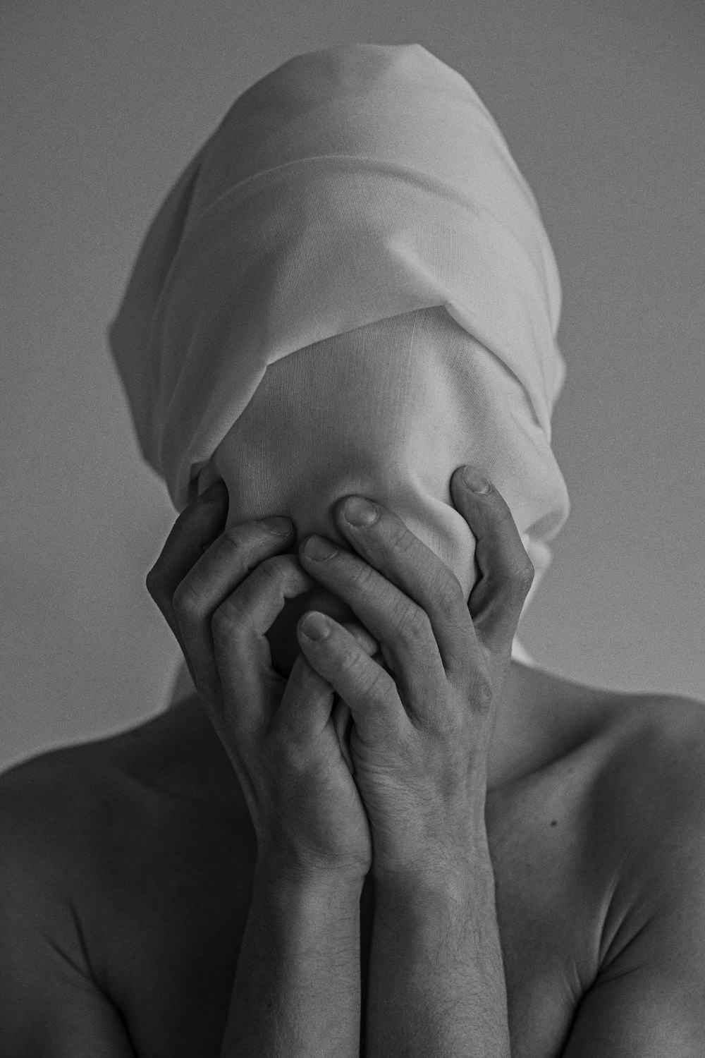 a shirtless woman covering her face with her hands