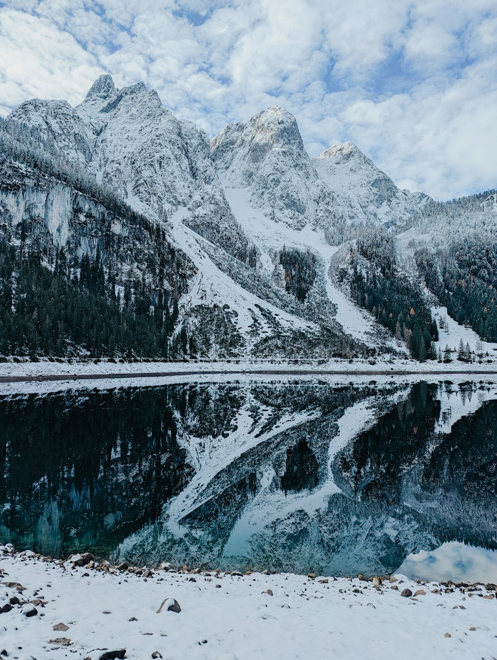 a snow covered mountain range with a lake in the foreground