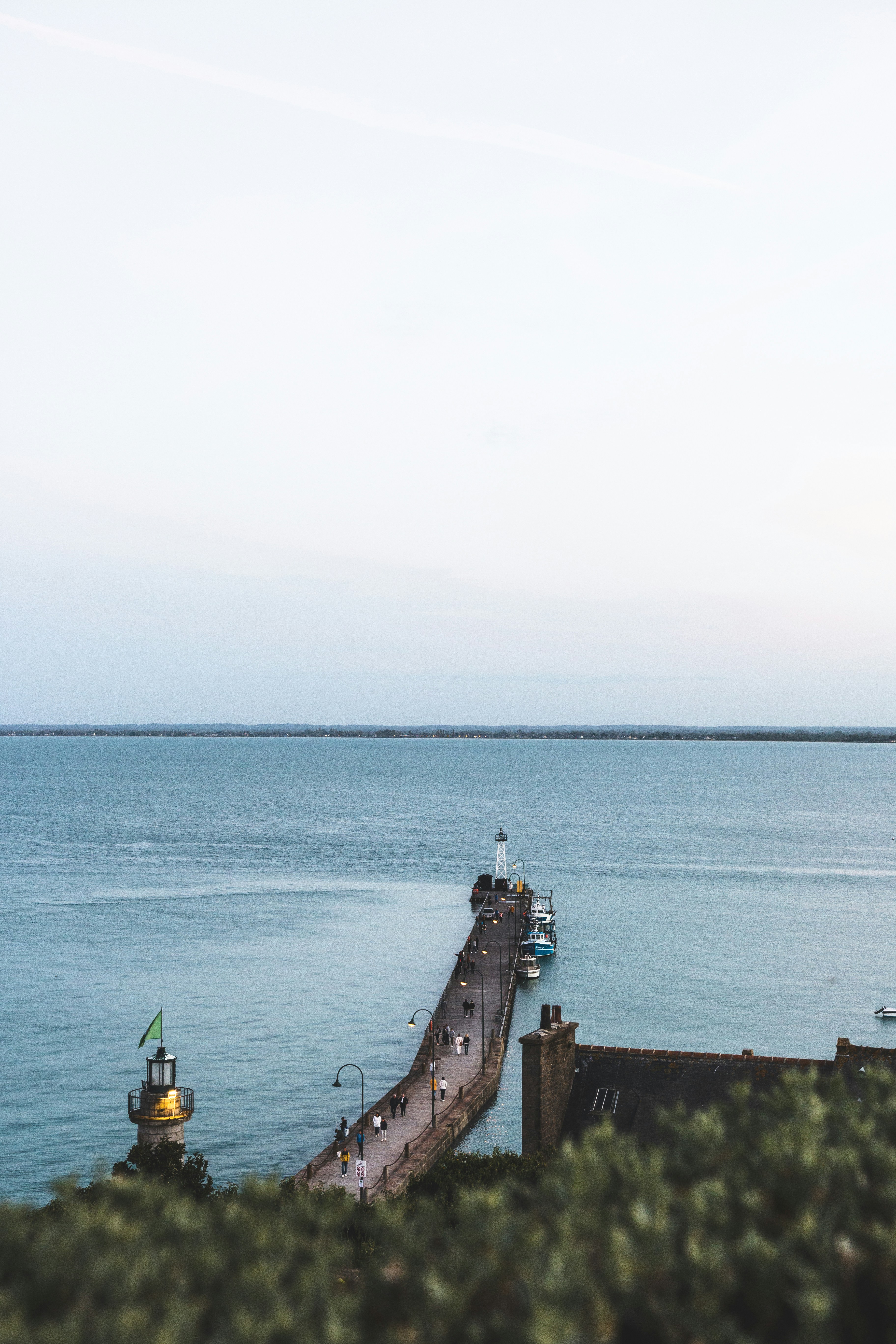 A long pier on the water with a boat in the distance photo – Free ...