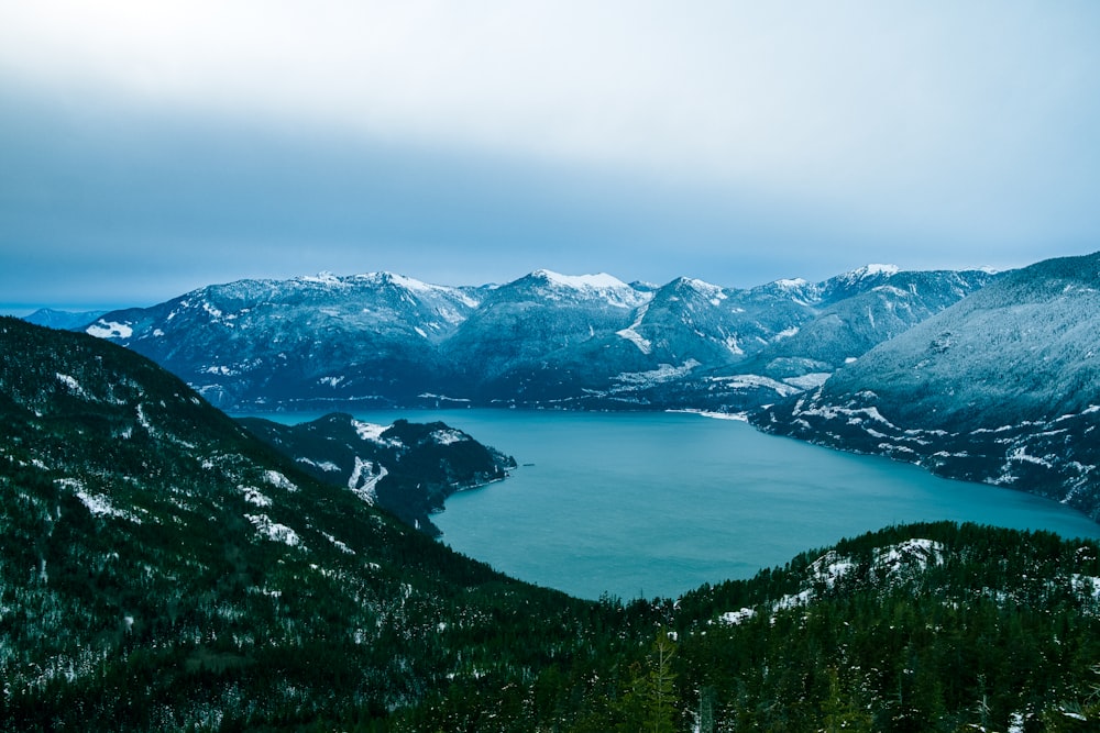 a view of a lake surrounded by snow covered mountains