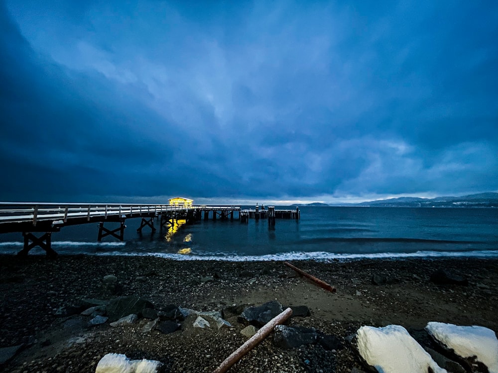 a pier on a beach with snow on the ground