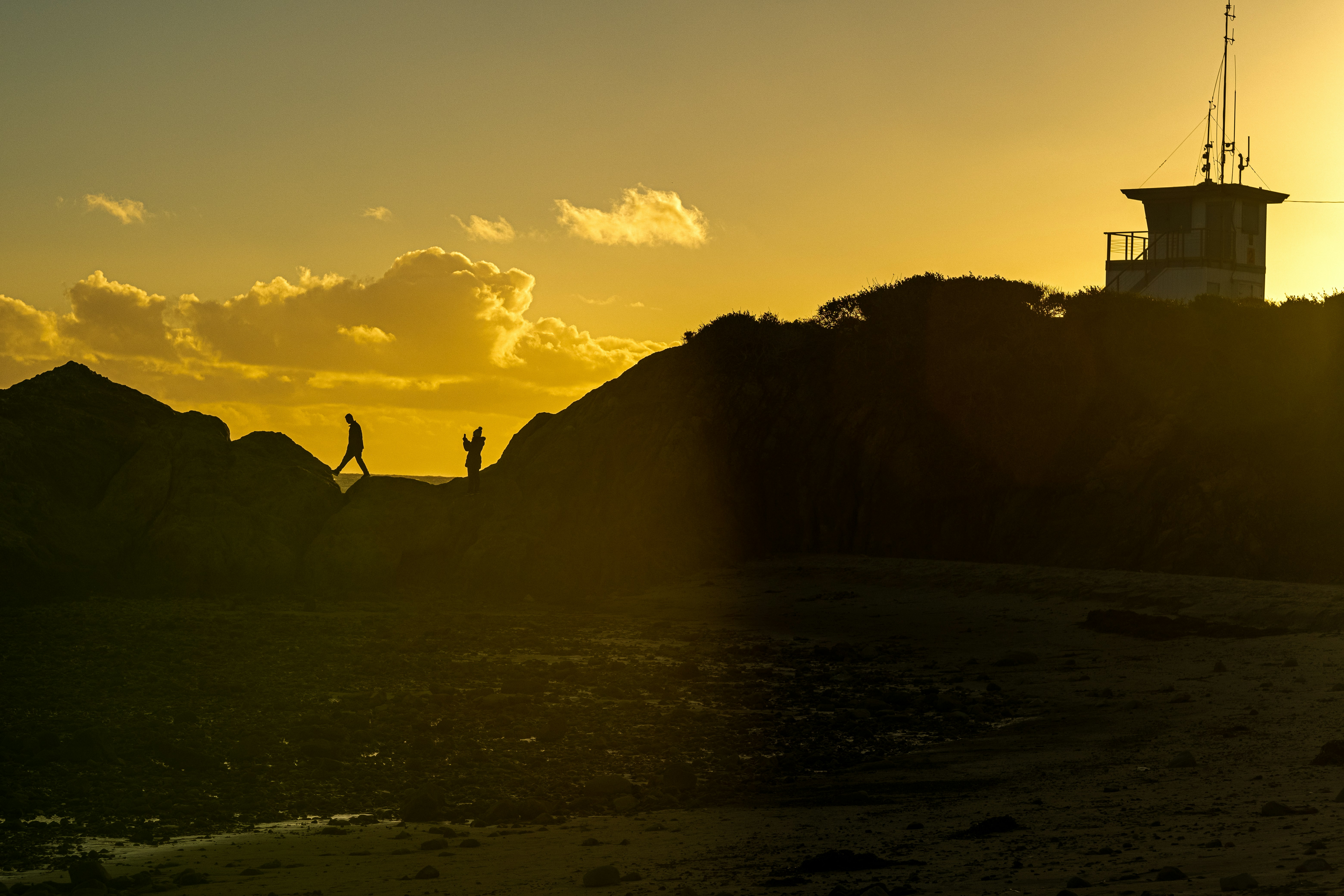 a couple of people standing on top of a sandy beach