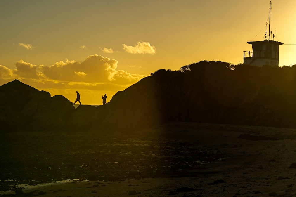 a couple of people standing on top of a sandy beach