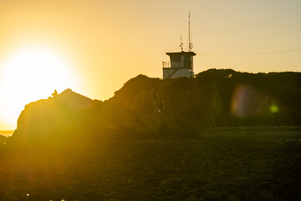 the sun is setting behind a lighthouse on a rocky shore
