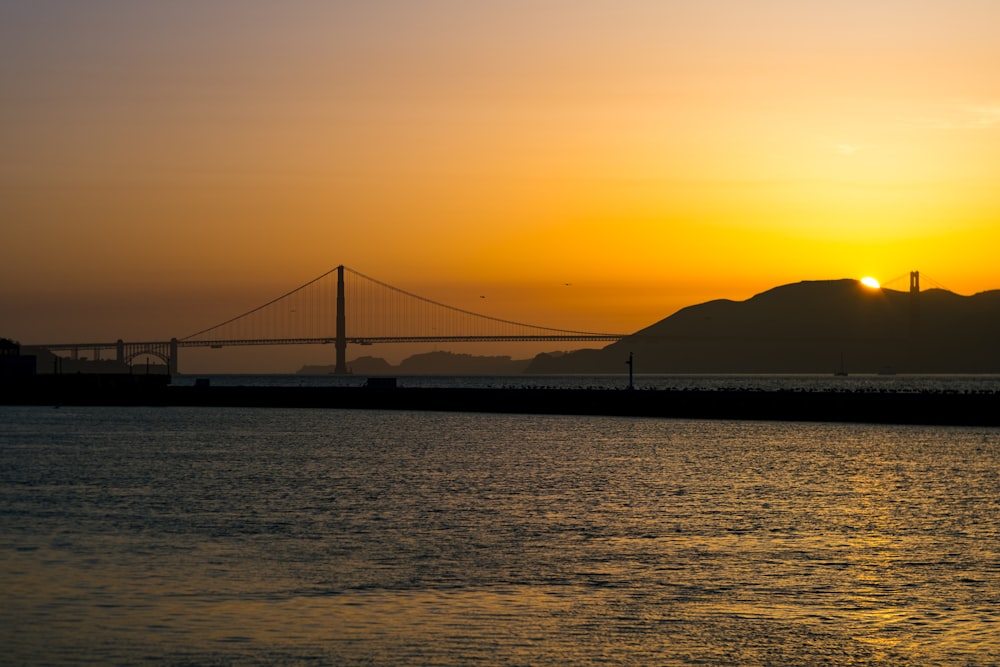 the sun is setting over the bay bridge