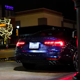 Modern sedan with dark tint reflecting city lights at night