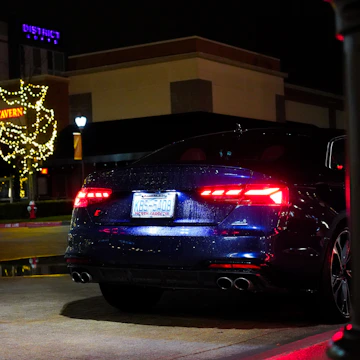 Modern sedan with dark tint reflecting city lights at night