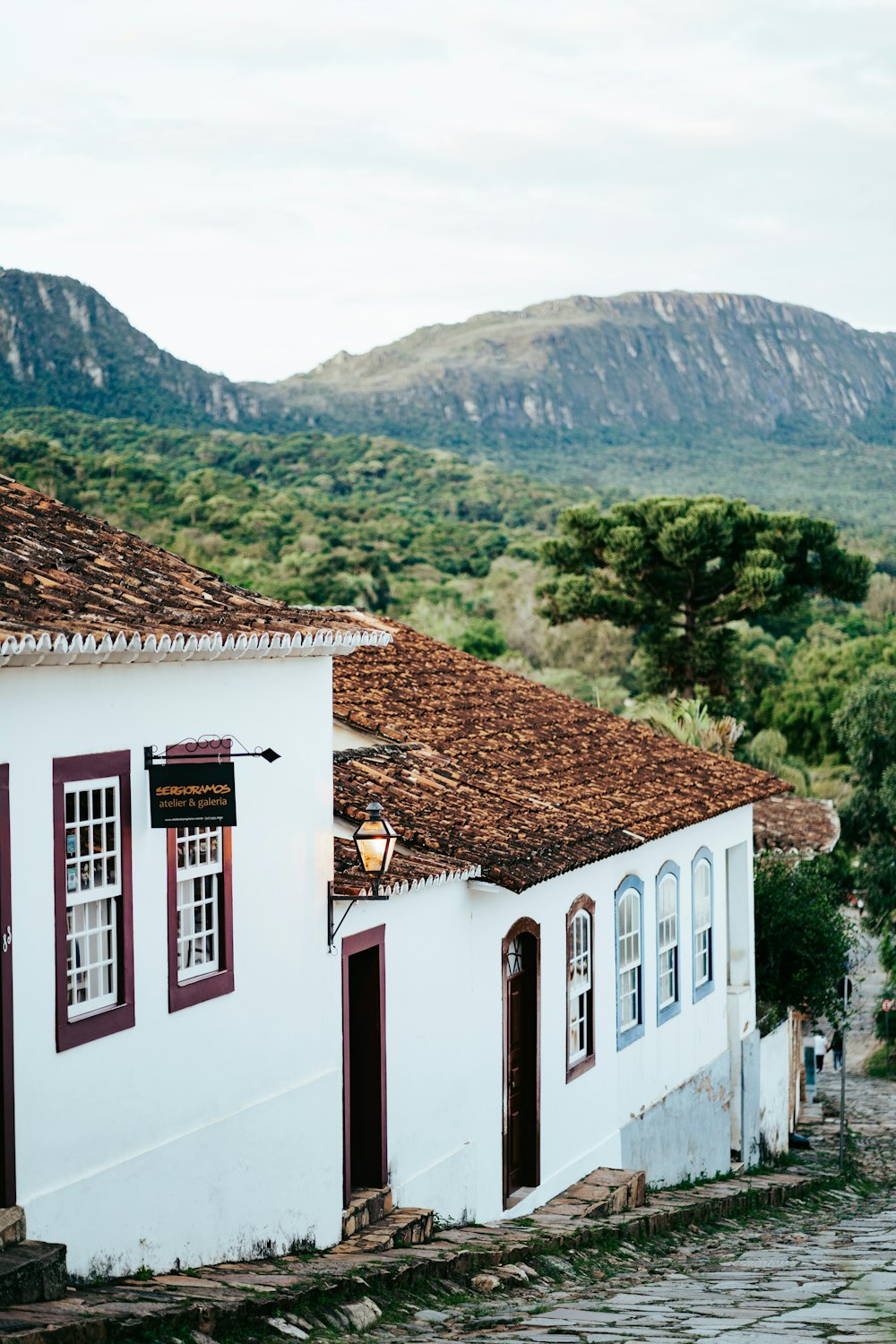 a white building with red shutters and a mountain in the background