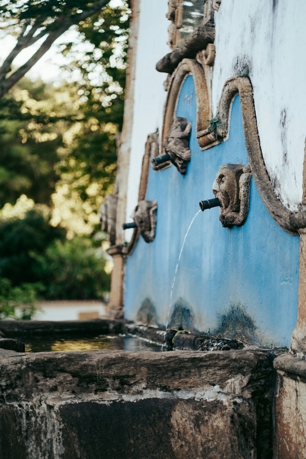 a blue wall with a water spigot attached to it