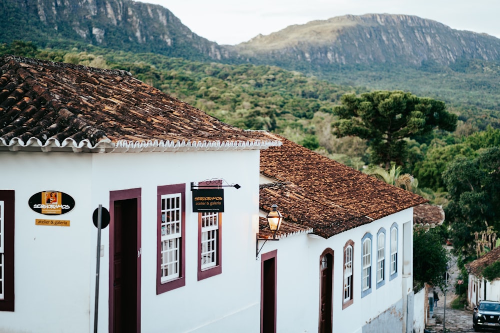 a white building with a brown roof and a mountain in the background