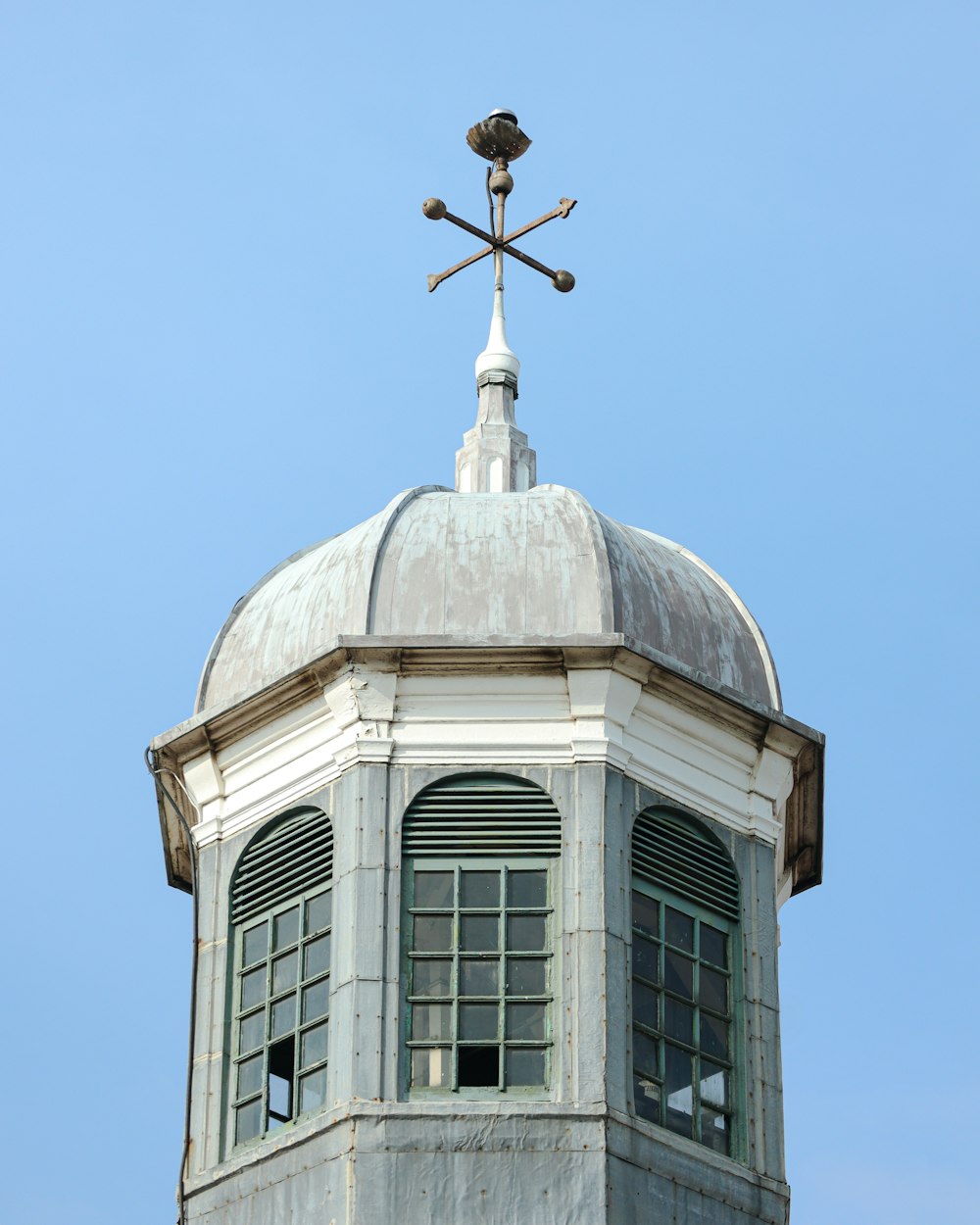 a tall white building with a weather vane on top of it