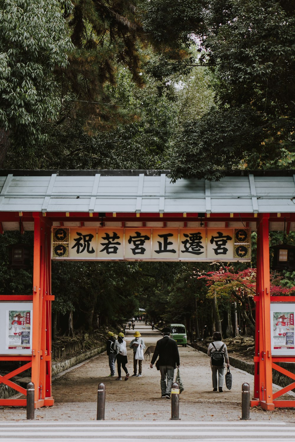 a group of people walking under a red gate