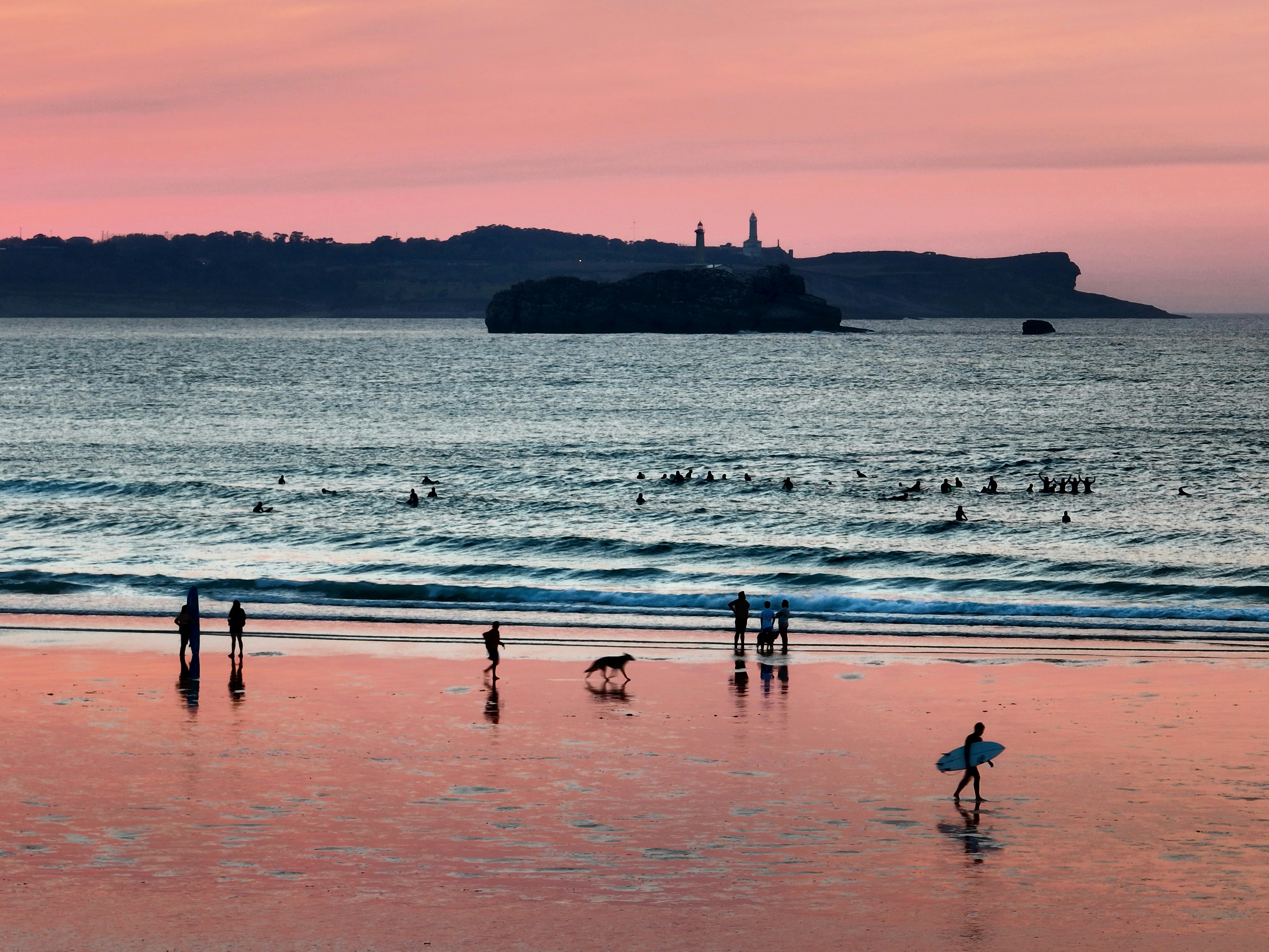 um grupo de pessoas em pé no topo de uma praia ao lado do oceano