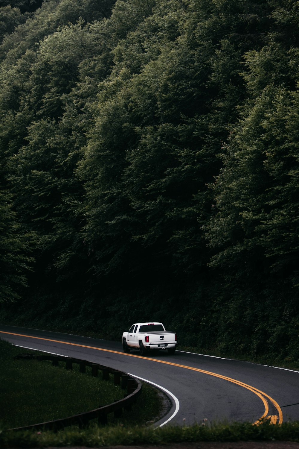 a white truck driving down a curvy road