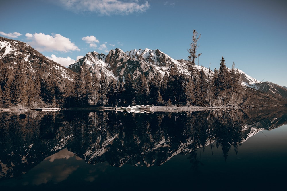 a lake surrounded by snow covered mountains and trees