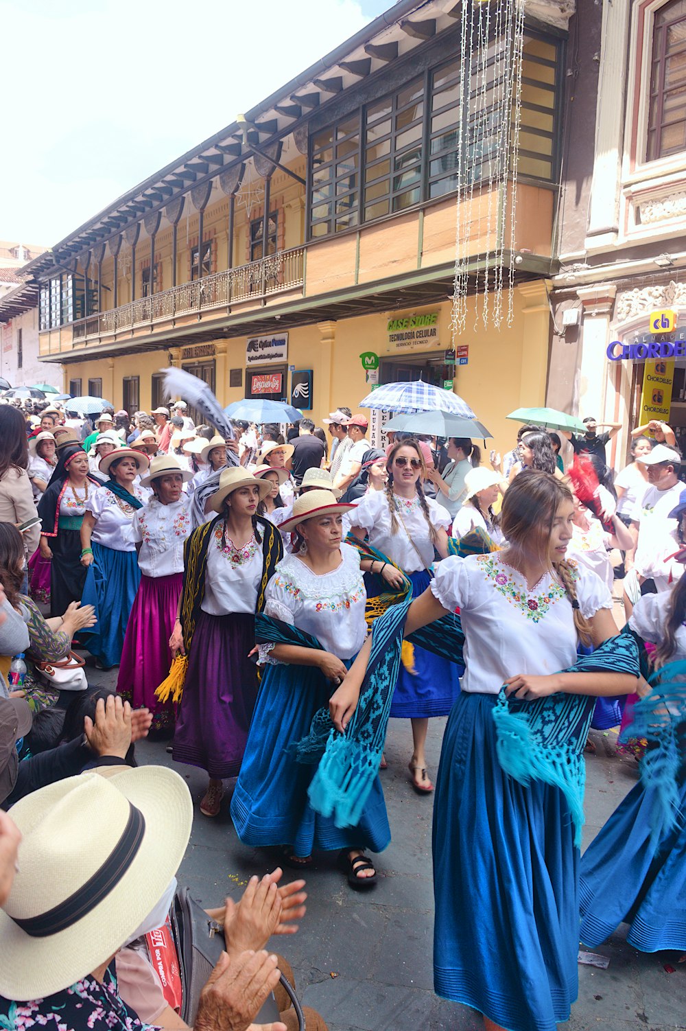a group of women in long dresses and hats dancing in the street
