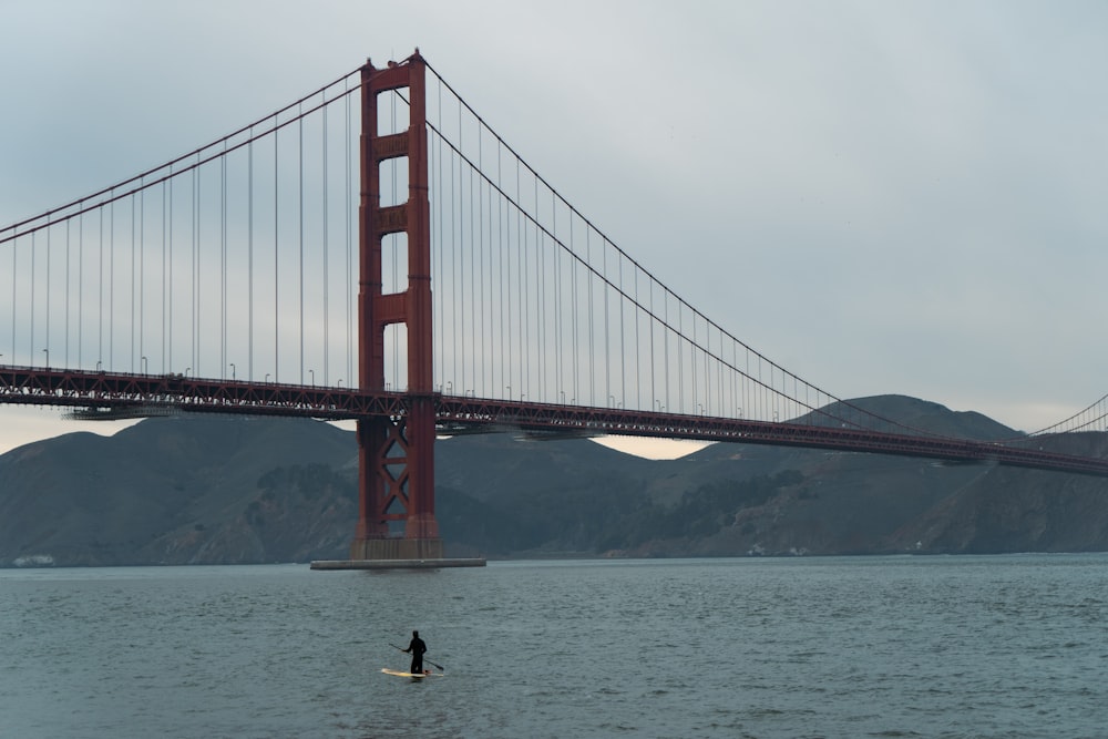 a person on a surfboard in front of the golden gate bridge