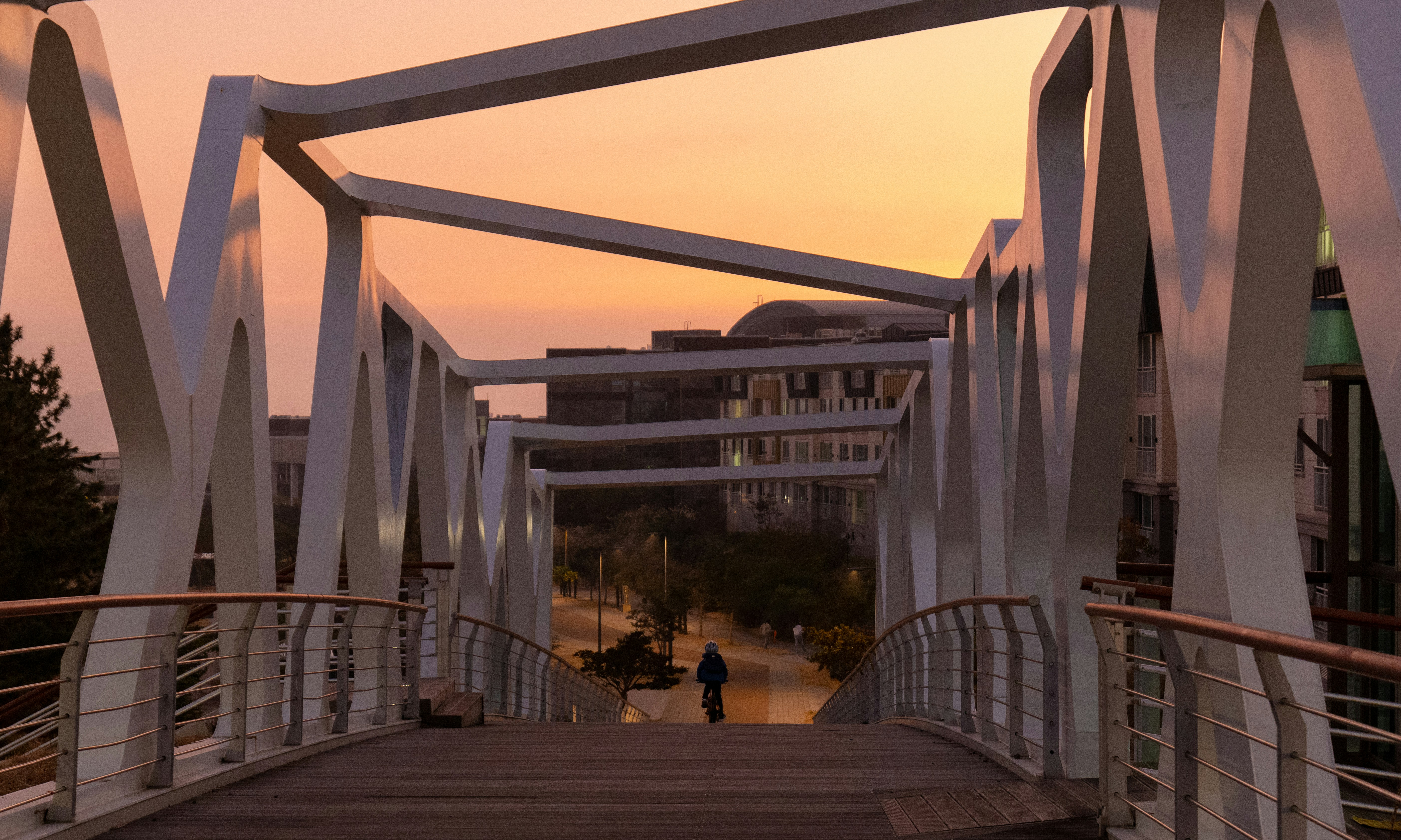 a person walking across a bridge at sunset