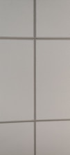 A pattern of rectangular, light-colored ceiling tiles with small perforations and visible grid lines.