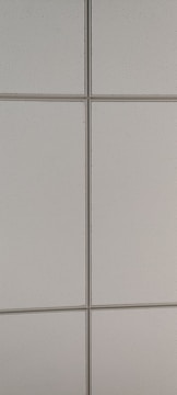 Close-up of hands fitting ceiling tiles into a suspended ceiling grid system.
