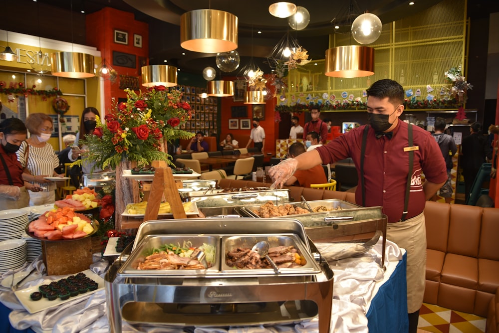 Un hombre parado frente a un buffet lleno de comida