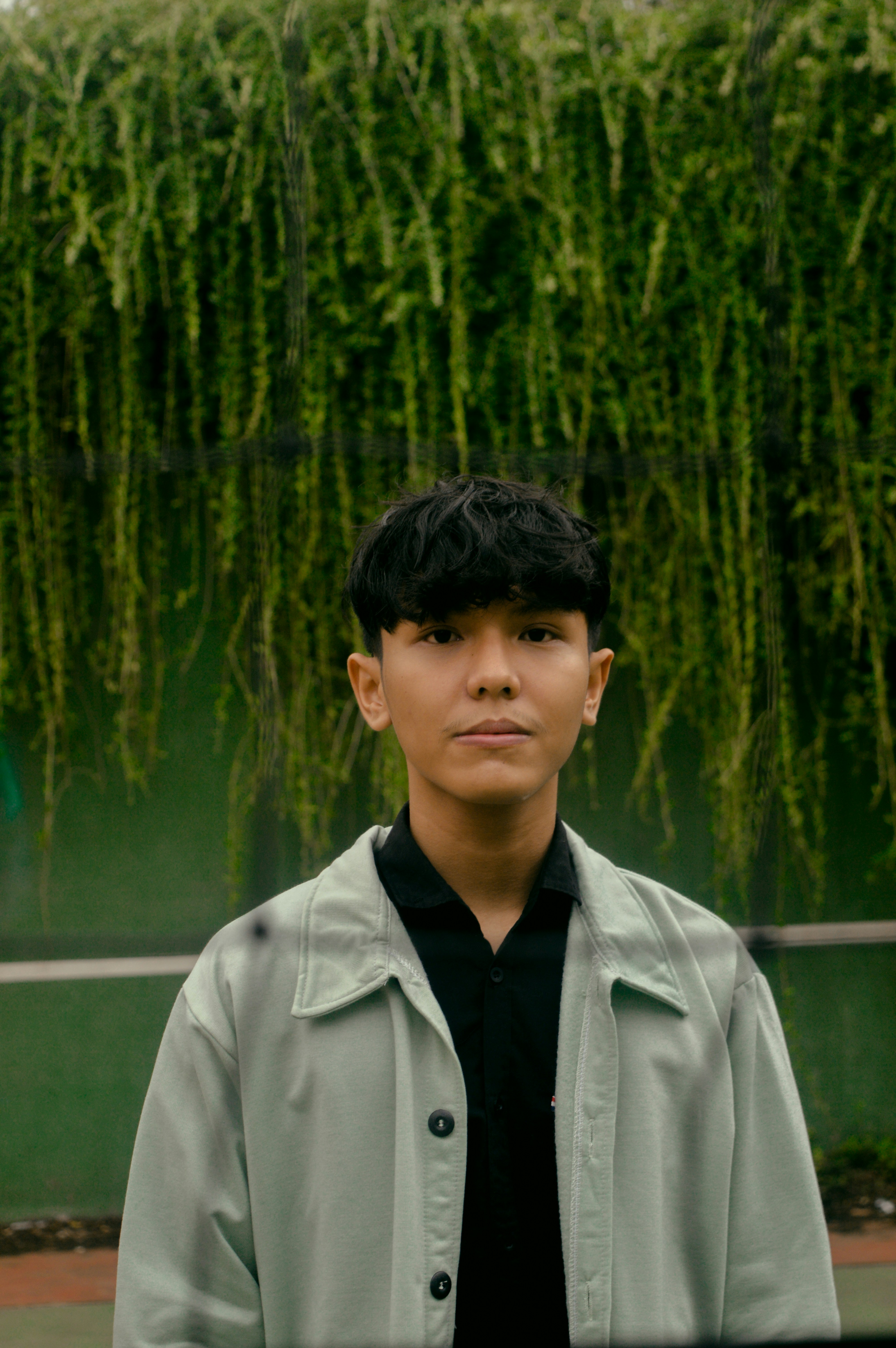 a young man standing in front of a green wall