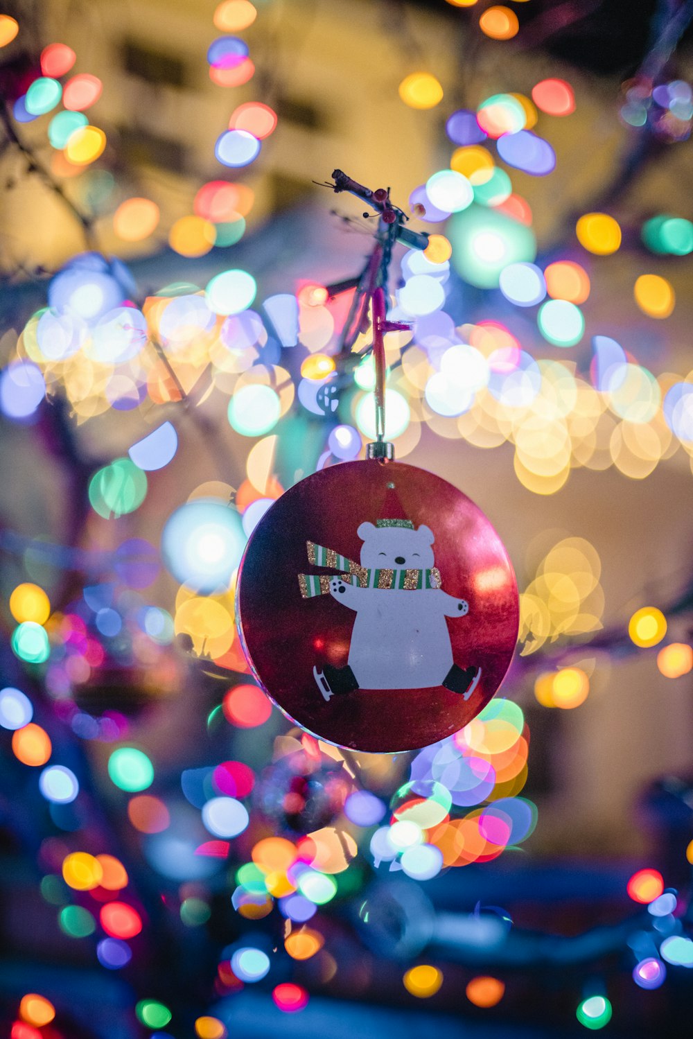 a christmas ornament hanging from a tree with lights in the background