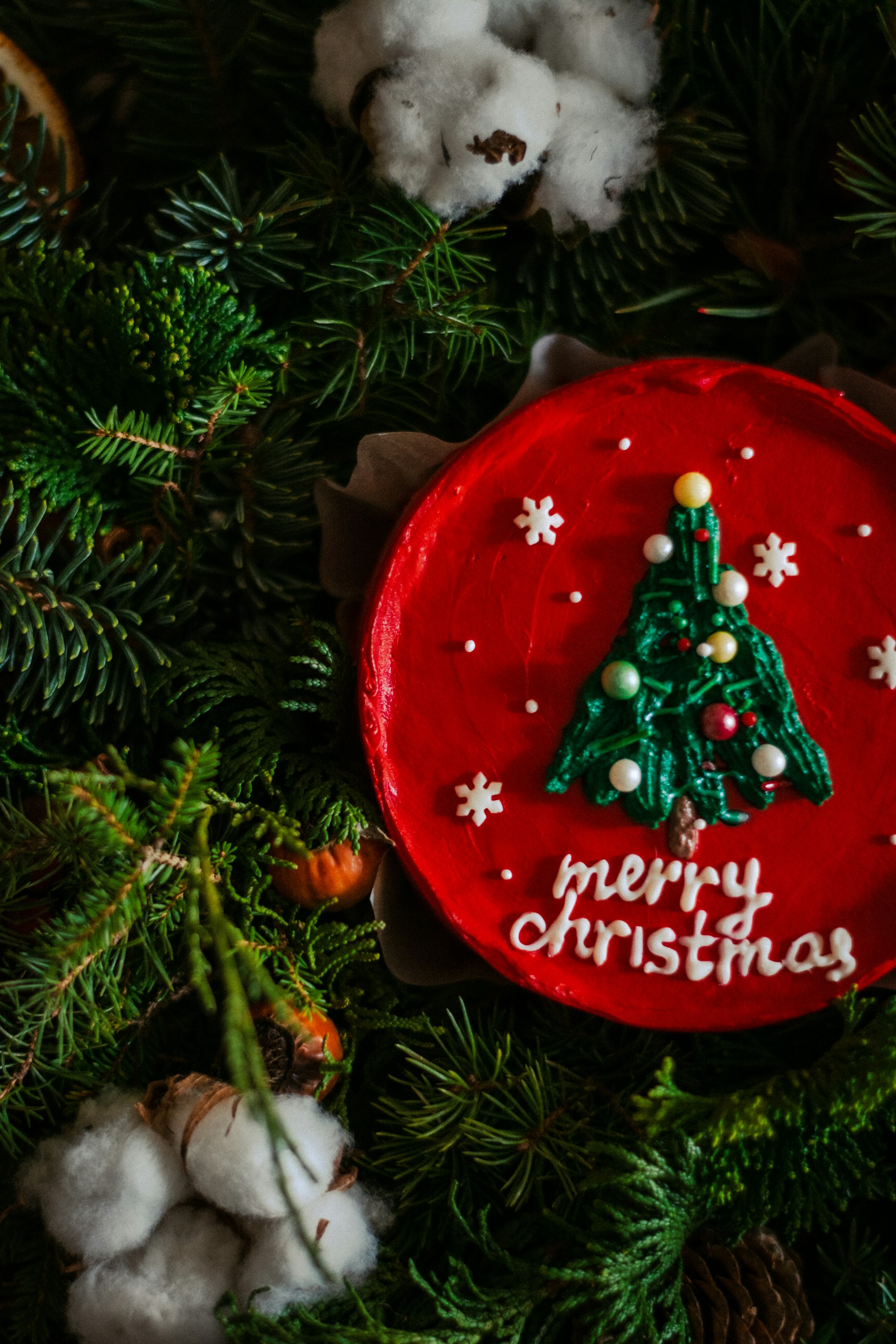 An elegant 8-inch Japanese sponge cake adorned with festive Christmas cupcake decorations shaped like tiny trees, set against a soft background in warm tones #f3e0c8 and #e6c9a8.