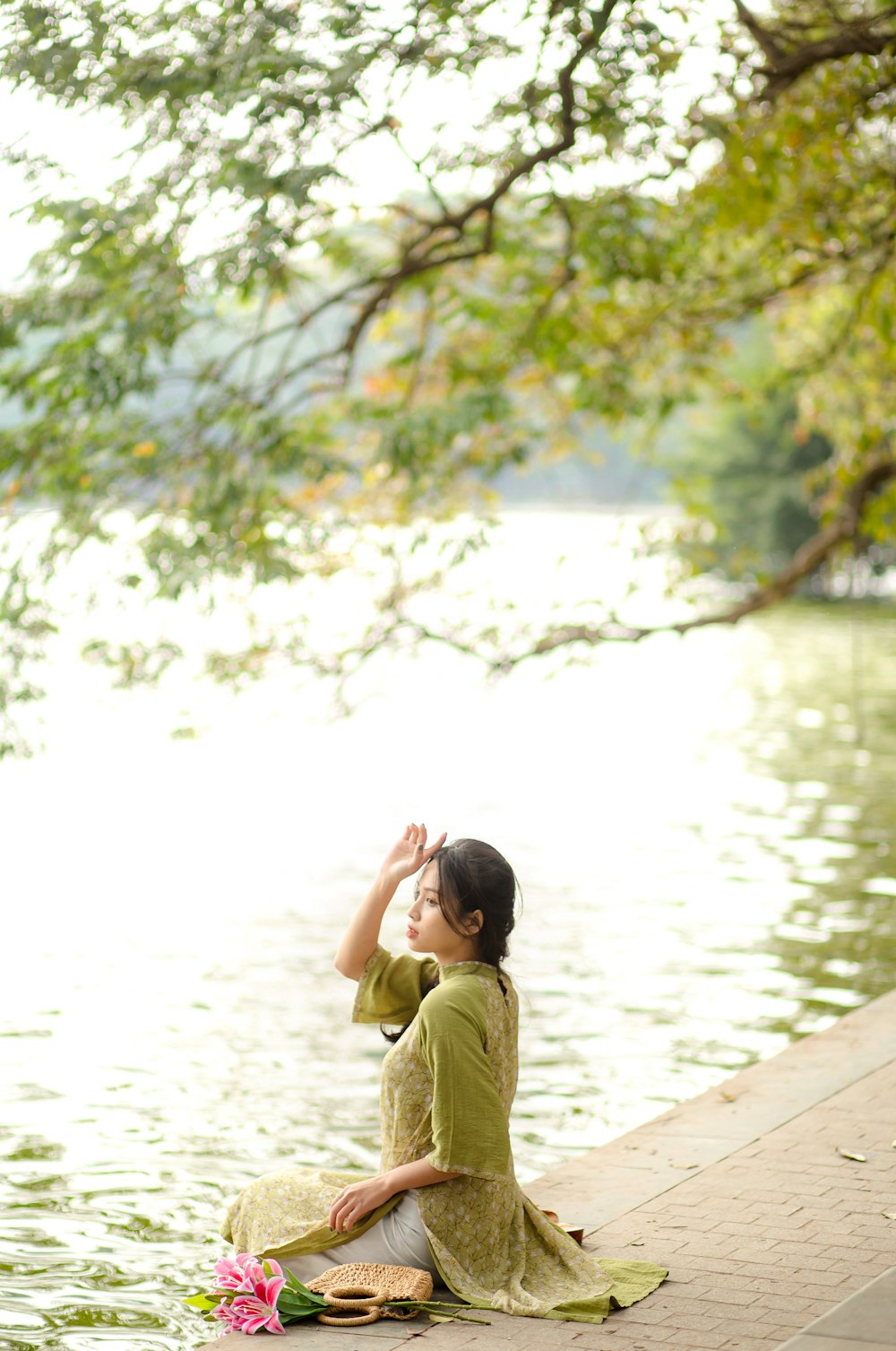 a woman sitting on the edge of a body of water