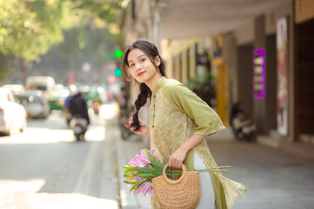 a woman holding a basket of flowers on a city street