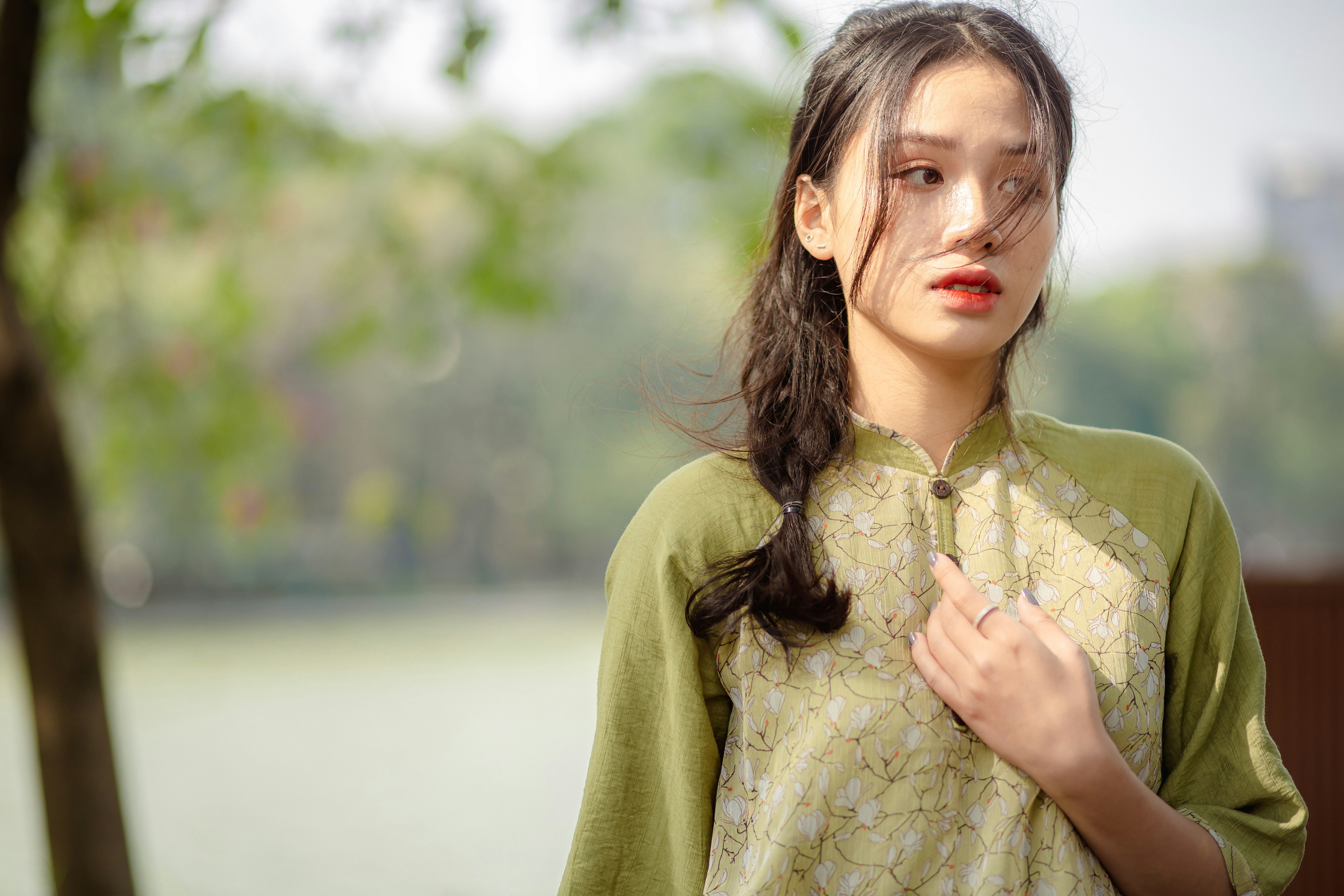 a woman with long hair standing next to a tree