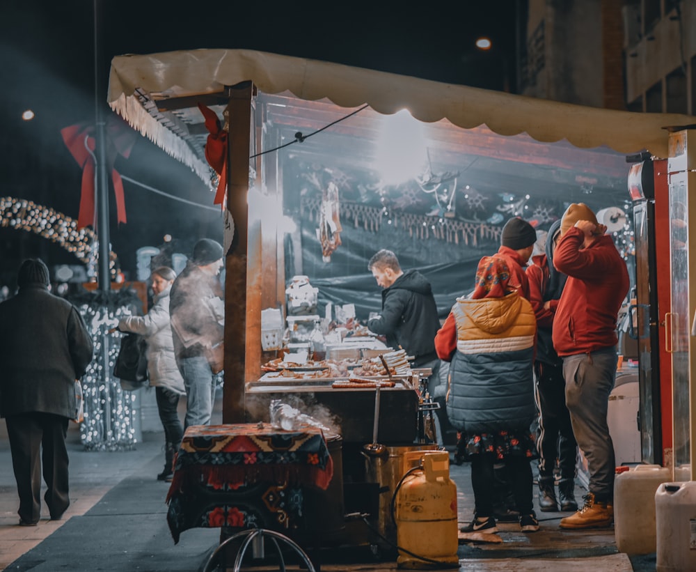 a group of people standing around a food stand