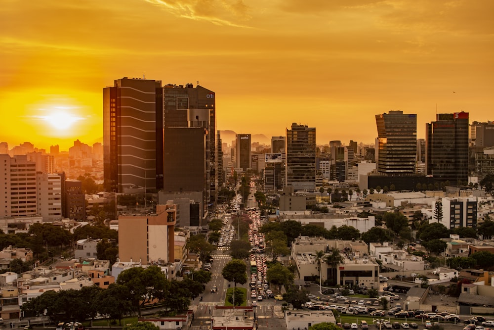 the sun is setting over a city with tall buildings